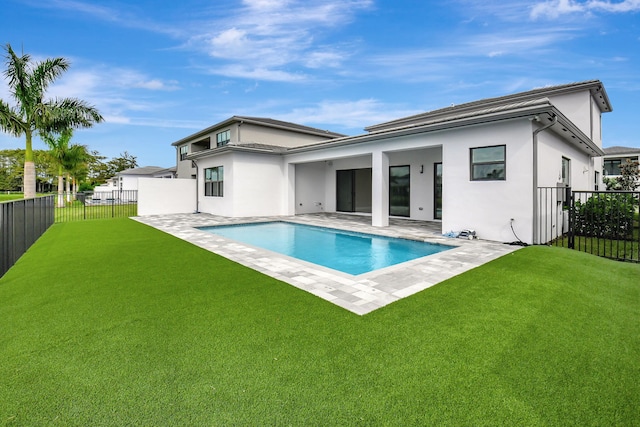 rear view of house featuring a patio area, a yard, and a fenced in pool