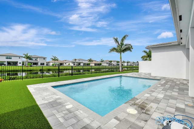 view of pool with a patio, a water view, and a lawn