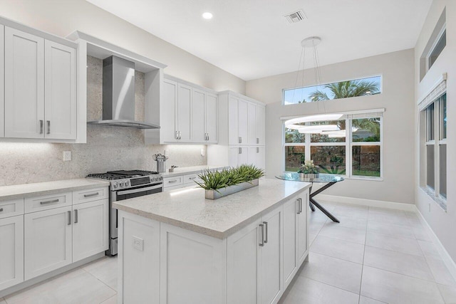 kitchen featuring gas range, white cabinetry, wall chimney exhaust hood, and a kitchen island