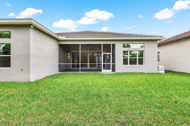 rear view of property featuring a yard, central air condition unit, and a sunroom