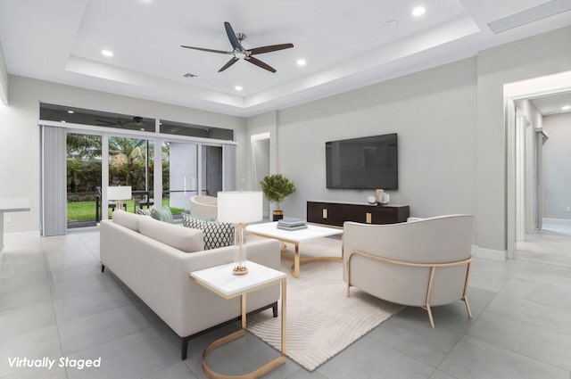 living room with a raised ceiling and ceiling fan