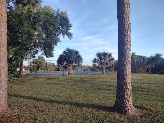 view of property's community with a lawn and tennis court