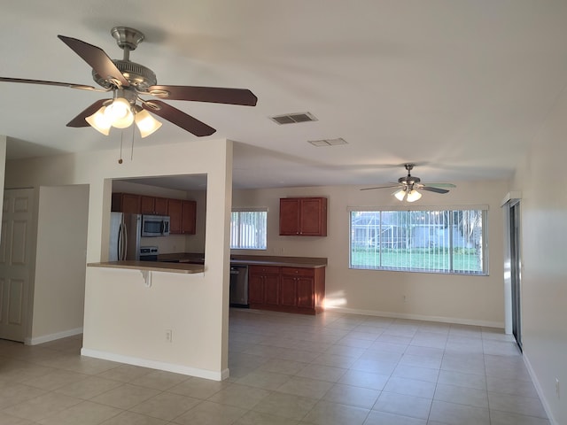 kitchen featuring kitchen peninsula, ceiling fan, light tile patterned floors, and stainless steel appliances