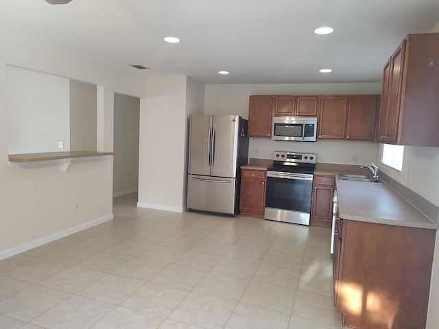 kitchen featuring kitchen peninsula, sink, light tile patterned floors, and stainless steel appliances