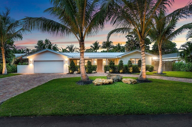 ranch-style home featuring a garage and a lawn