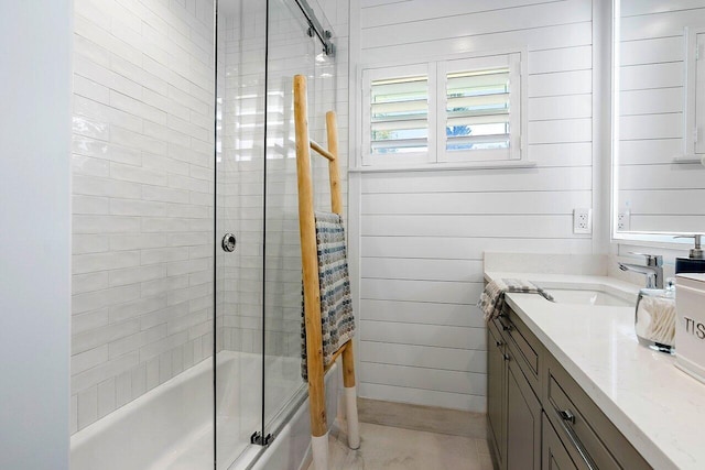 bathroom featuring vanity, wood walls, and bath / shower combo with glass door