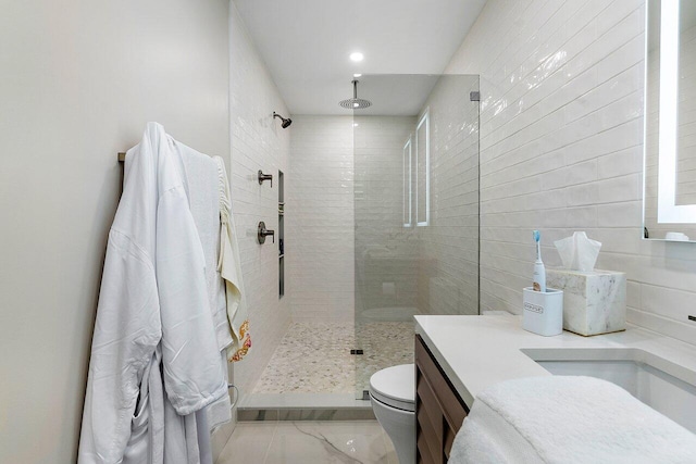 bathroom with a tile shower, vanity, and toilet