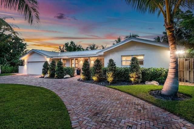 single story home featuring a lawn and a garage