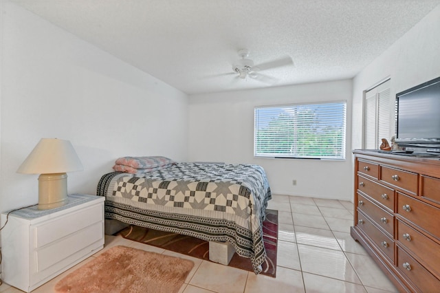 bedroom featuring ceiling fan, a textured ceiling, light tile patterned floors, and a closet