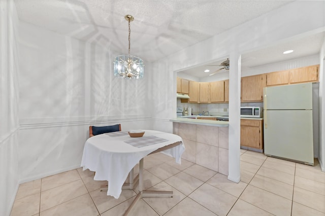 tiled dining area featuring ceiling fan with notable chandelier and a textured ceiling