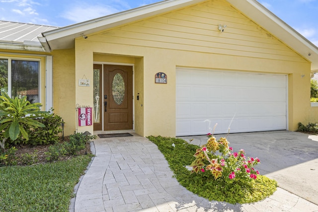 view of front of home with stucco siding, driveway, metal roof, and a standing seam roof