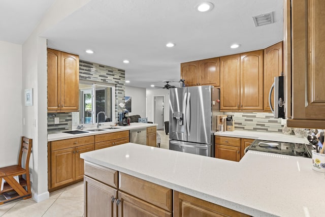 kitchen with visible vents, light stone countertops, decorative backsplash, appliances with stainless steel finishes, and a sink