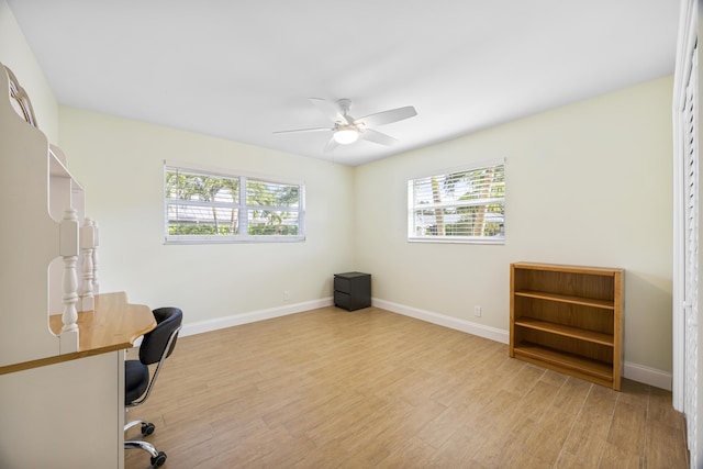 unfurnished office featuring a ceiling fan, baseboards, and light wood finished floors