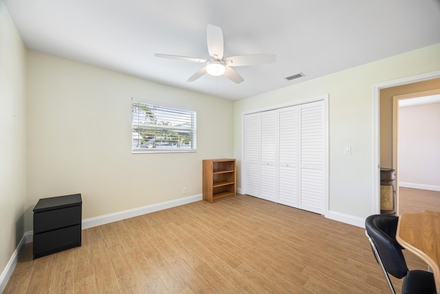 bedroom with light wood-type flooring, visible vents, baseboards, and a closet