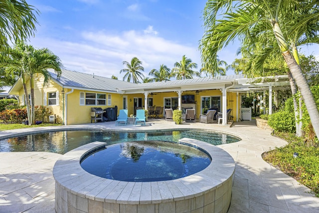 view of pool with grilling area, a pool with connected hot tub, ceiling fan, and a patio area