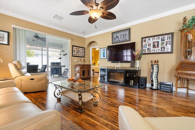 225 SW Coconut Key Way, Port Saint Lucie, FL 34986 - living room featuring a ceiling fan, arched walkways, wood finished floors, ornamental molding, and a glass covered fireplace