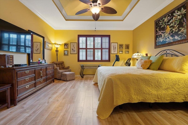 bedroom featuring a raised ceiling, ceiling fan, light wood-type flooring, and ornamental molding