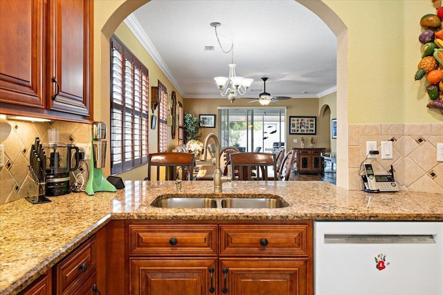 kitchen with white dishwasher, ceiling fan with notable chandelier, sink, crown molding, and light stone counters