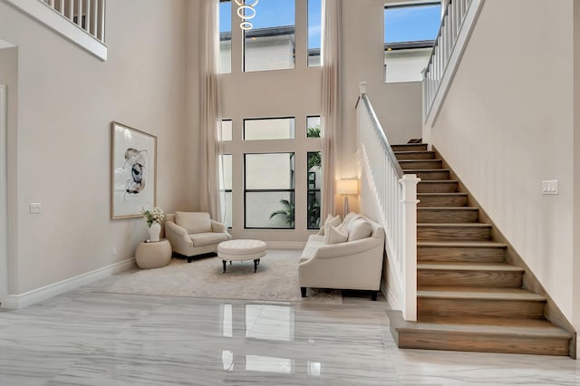 foyer with marble finish floor, stairway, a towering ceiling, and baseboards