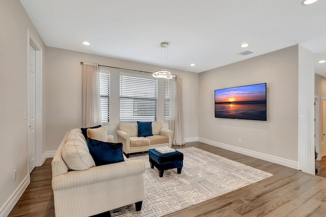 living area with recessed lighting, visible vents, baseboards, and wood finished floors