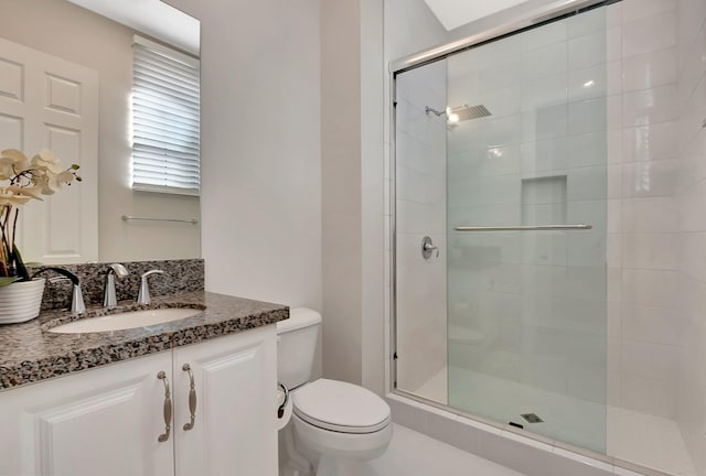 full bathroom featuring tiled shower, vanity, and toilet