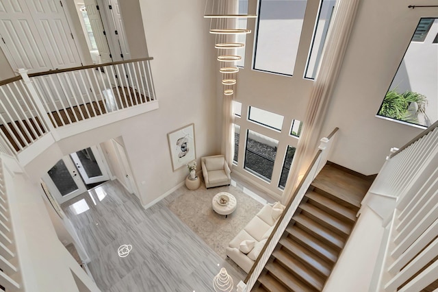 living room with a towering ceiling, baseboards, and wood finished floors