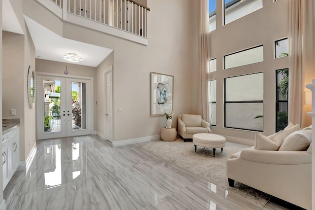 interior space with french doors, a high ceiling, marble finish floor, and baseboards