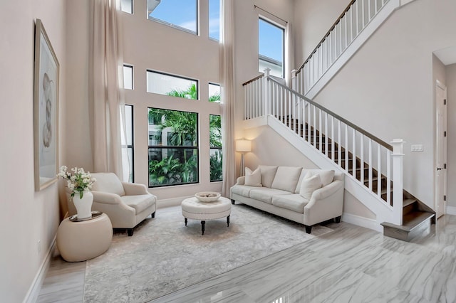 living area with stairway, a high ceiling, and baseboards