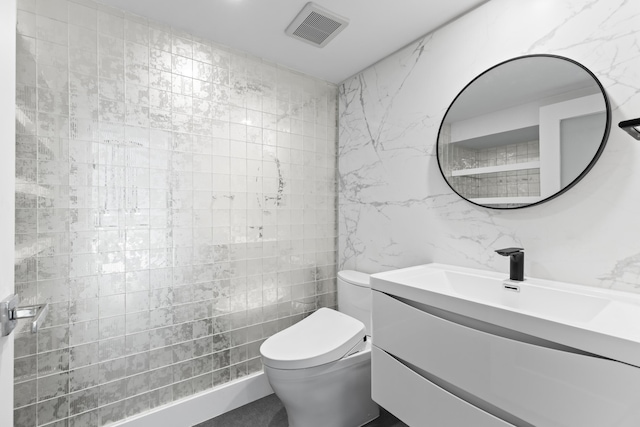 bathroom featuring vanity, toilet, and tile walls