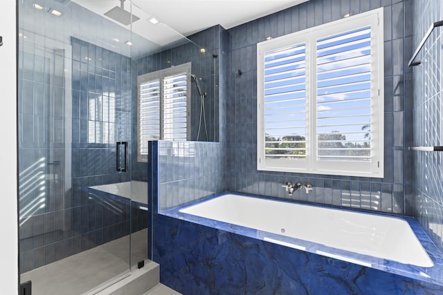 bathroom featuring shower with separate bathtub, plenty of natural light, and tile walls