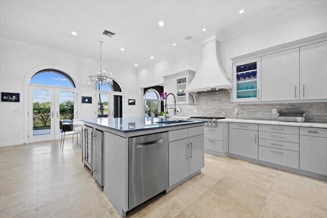 kitchen featuring sink, stainless steel appliances, plenty of natural light, a kitchen island with sink, and custom range hood