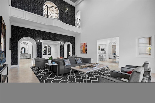 tiled living room featuring crown molding, a high ceiling, and an inviting chandelier