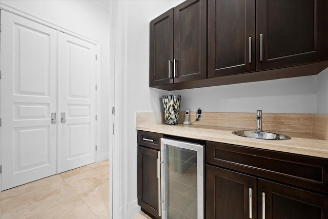 kitchen featuring dark brown cabinets, light tile patterned floors, sink, and beverage cooler