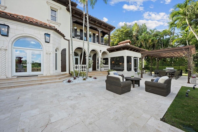 rear view of house featuring a balcony, a pergola, a patio, and french doors