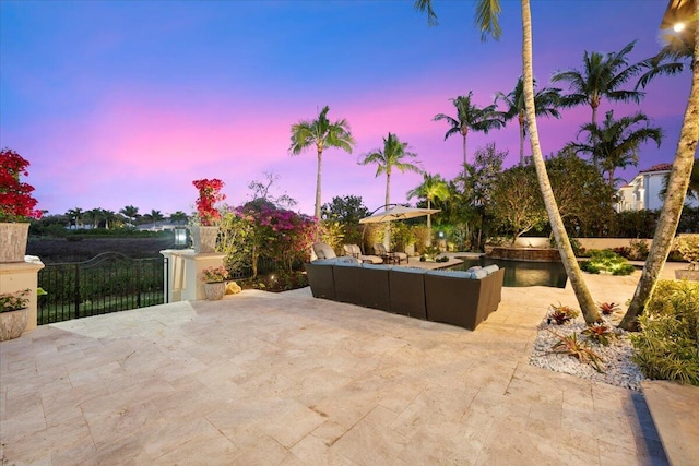 patio terrace at dusk with an outdoor hangout area and a water view