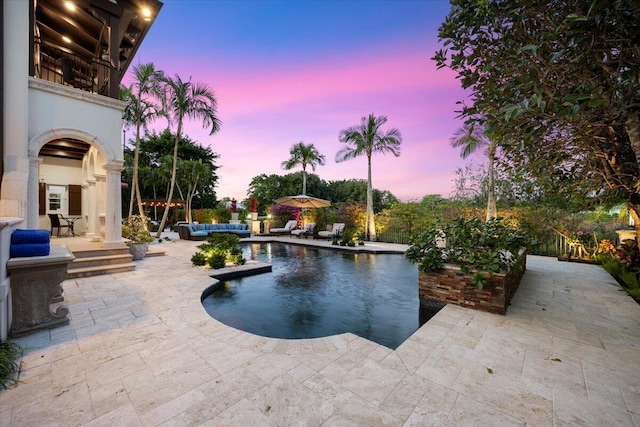 pool at dusk featuring a patio area