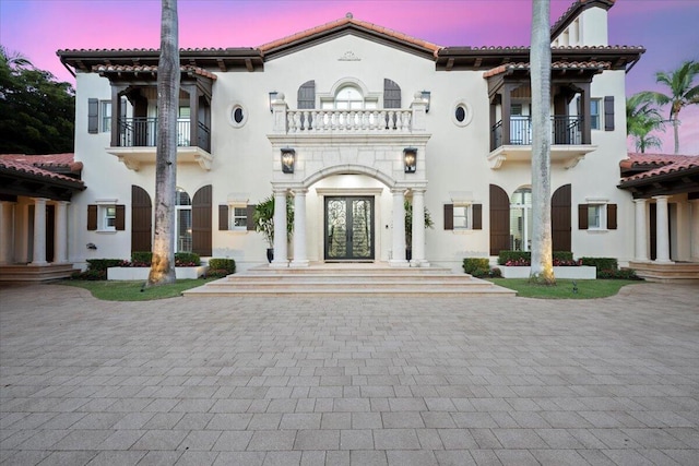 mediterranean / spanish house featuring a balcony and french doors