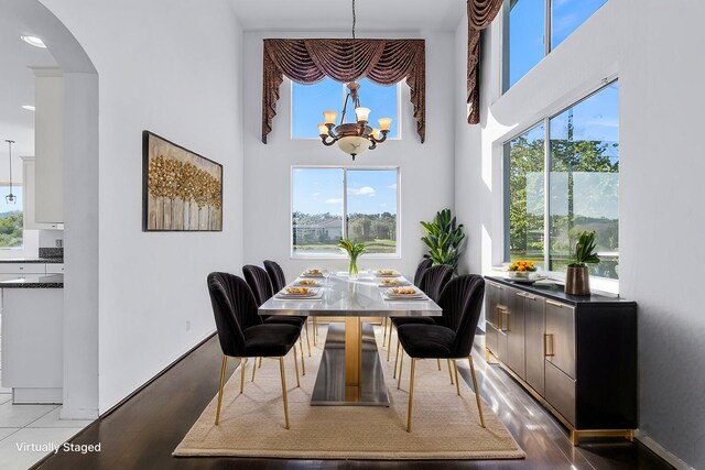 empty room featuring hardwood / wood-style floors, a towering ceiling, and a notable chandelier