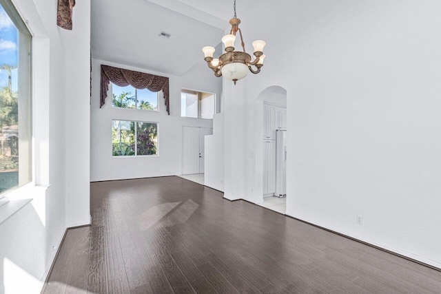 unfurnished room featuring a high ceiling, wood-type flooring, a notable chandelier, and beam ceiling