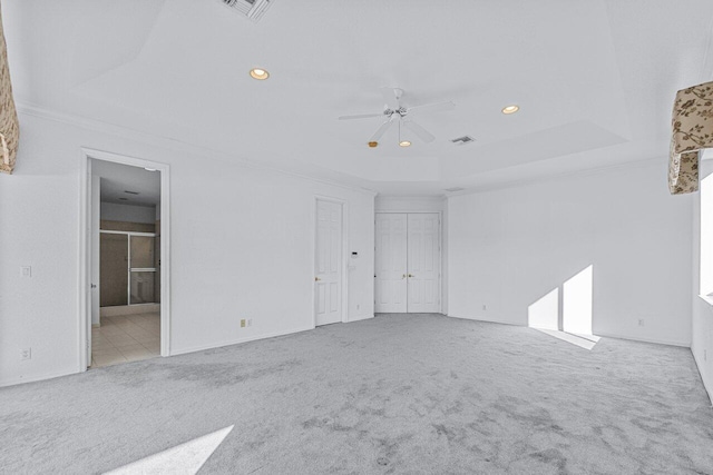 carpeted spare room with a tray ceiling, ceiling fan, and ornamental molding