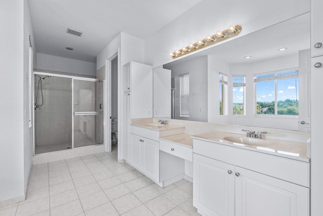 bathroom featuring tile patterned floors, vanity, a shower with shower door, and toilet