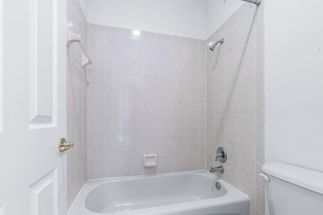 bathroom featuring toilet and tiled shower / bath