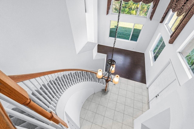 stairs featuring tile patterned flooring, a towering ceiling, and a chandelier