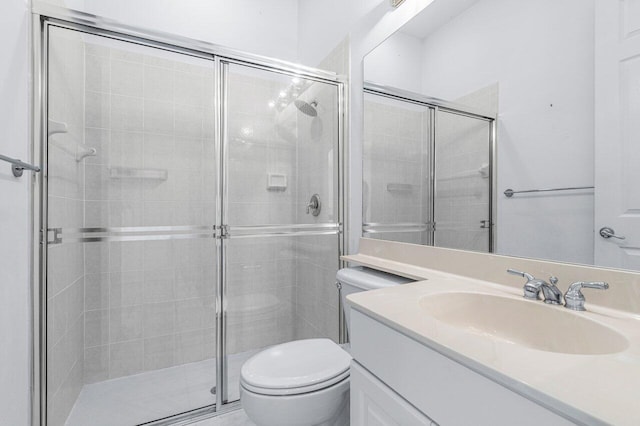 bathroom featuring vanity, toilet, and a shower with shower door