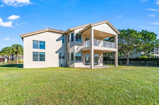 rear view of property featuring a lawn, a balcony, and a patio