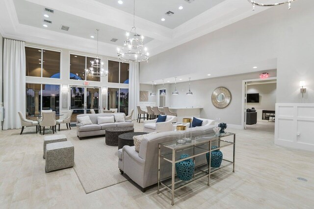 living room featuring a towering ceiling, ornamental molding, beam ceiling, and a notable chandelier