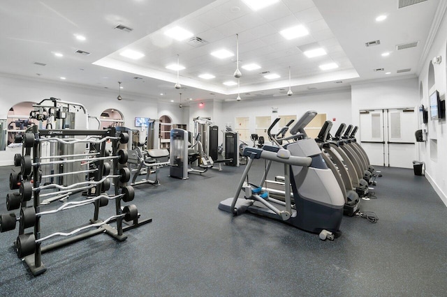 gym with ornamental molding, a raised ceiling, and a drop ceiling