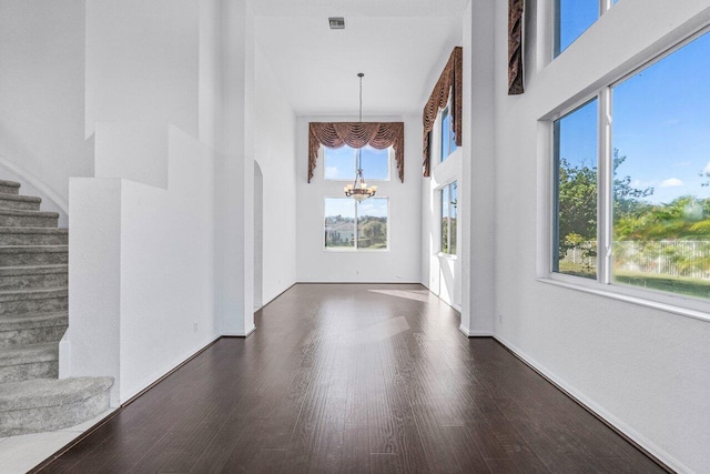 hallway with dark hardwood / wood-style flooring, a high ceiling, and an inviting chandelier