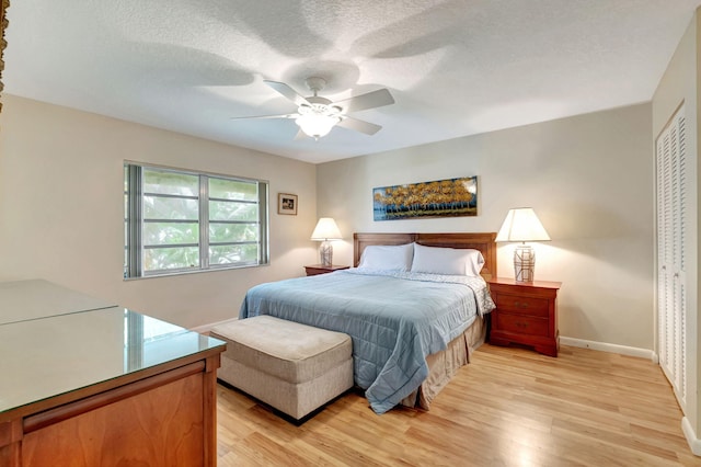 bedroom with a textured ceiling, a closet, light hardwood / wood-style floors, and ceiling fan