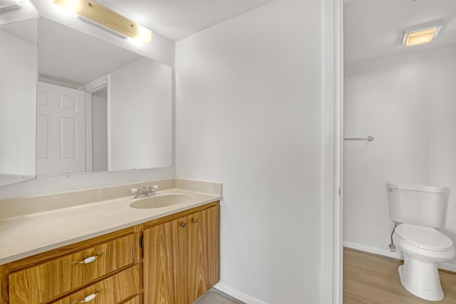 bathroom featuring wood-type flooring, vanity, and toilet